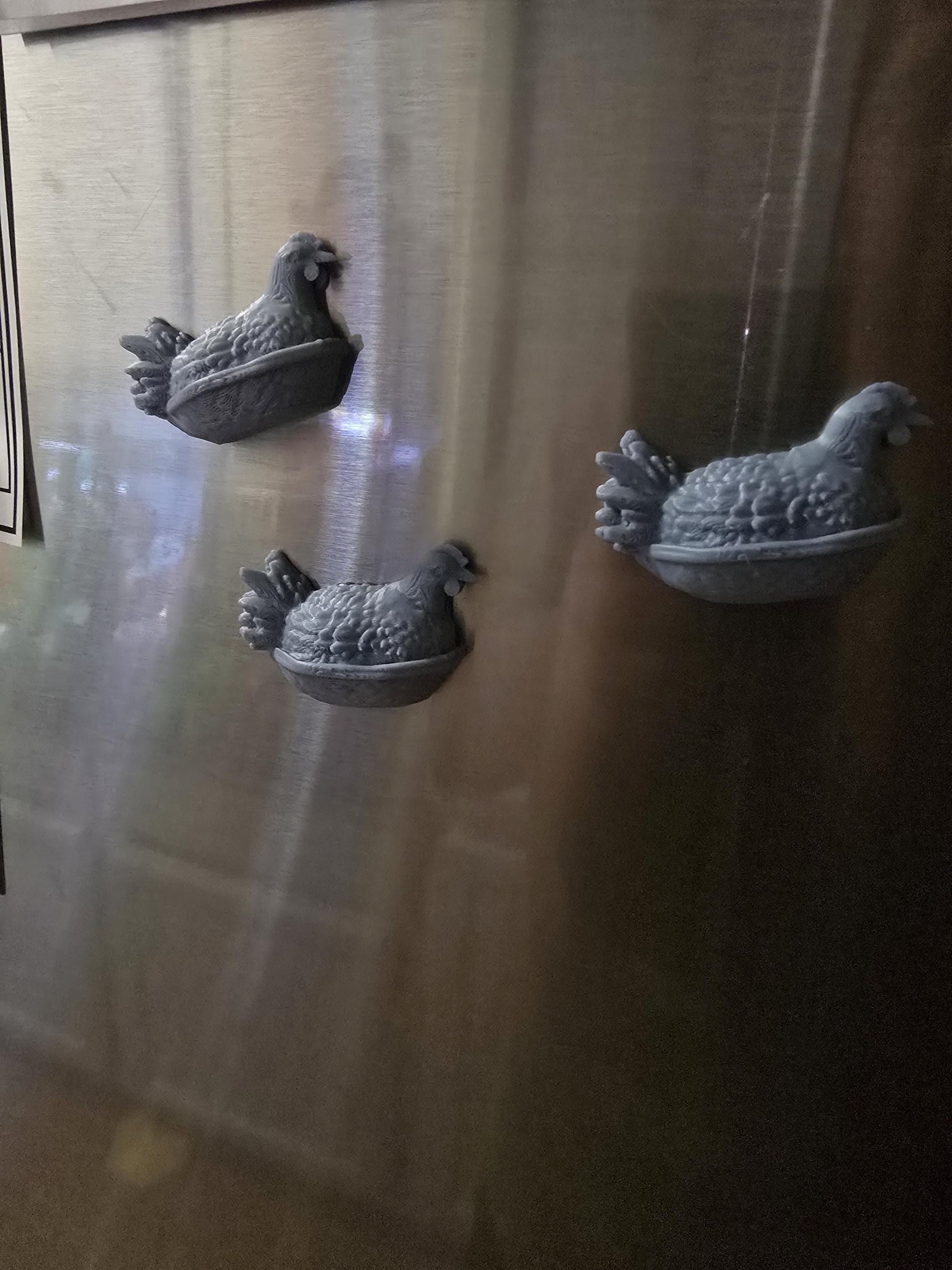 Chicken magnets holding paper on a fridge