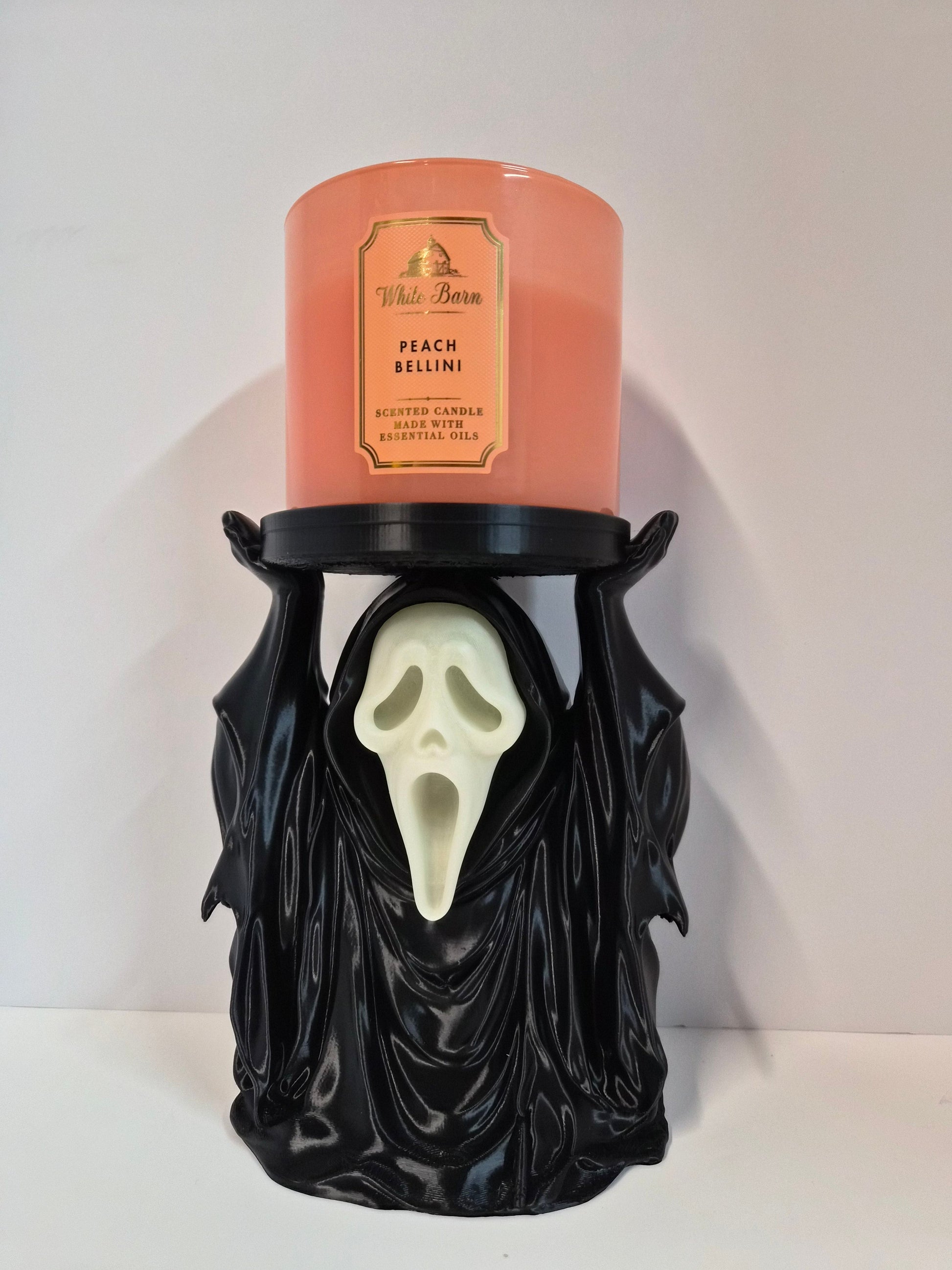 Hooded phantom candle holder holding a jar candle, glow-in-the-dark face, front view